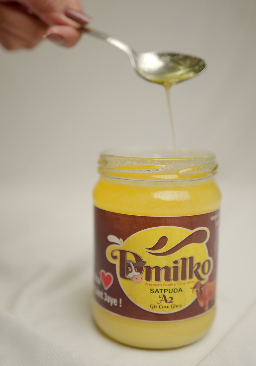 A spoonful of D'Milko ghee being lifted from the jar